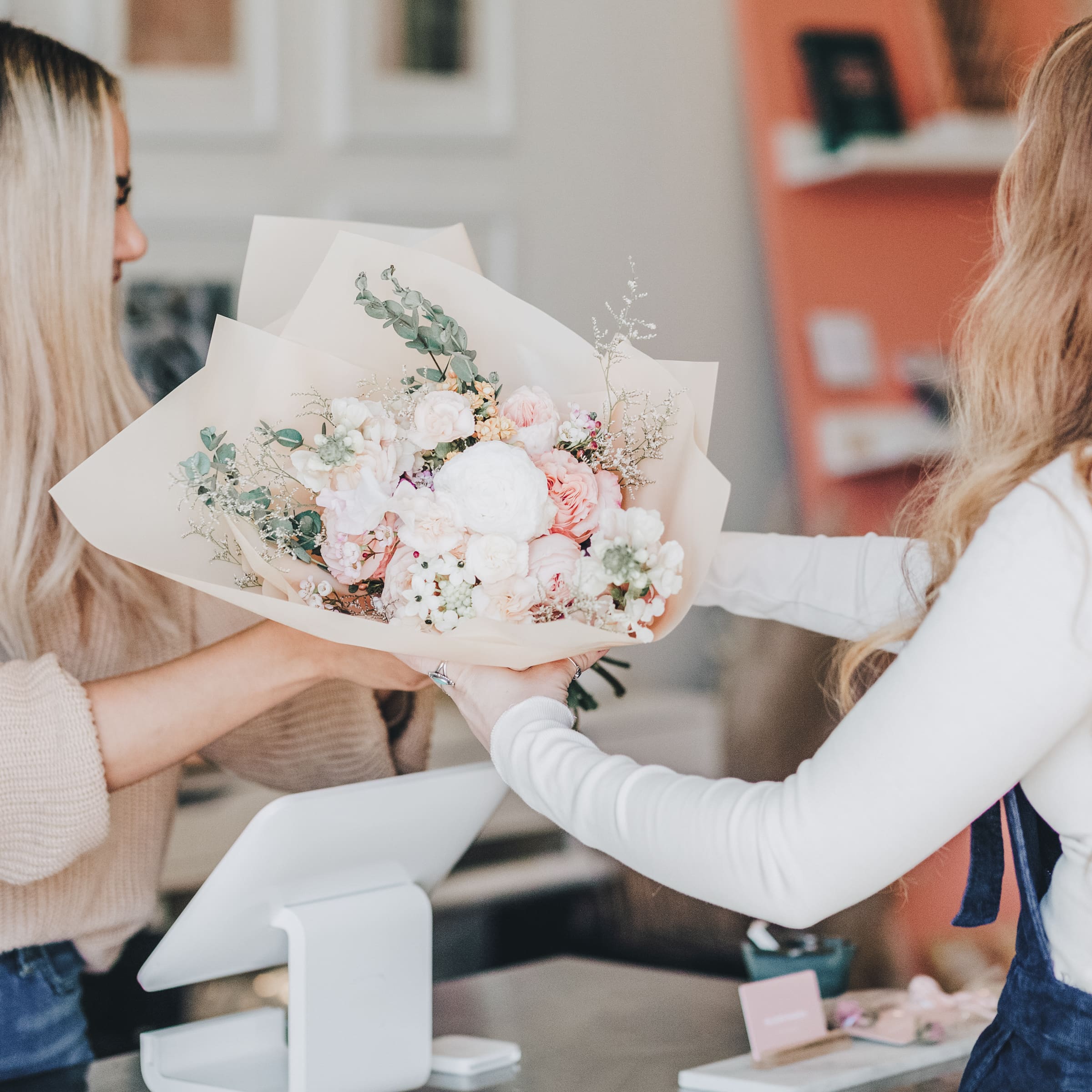 Two women exchanging a bouquet of flowers, symbolizing connection, care, and self-worth.