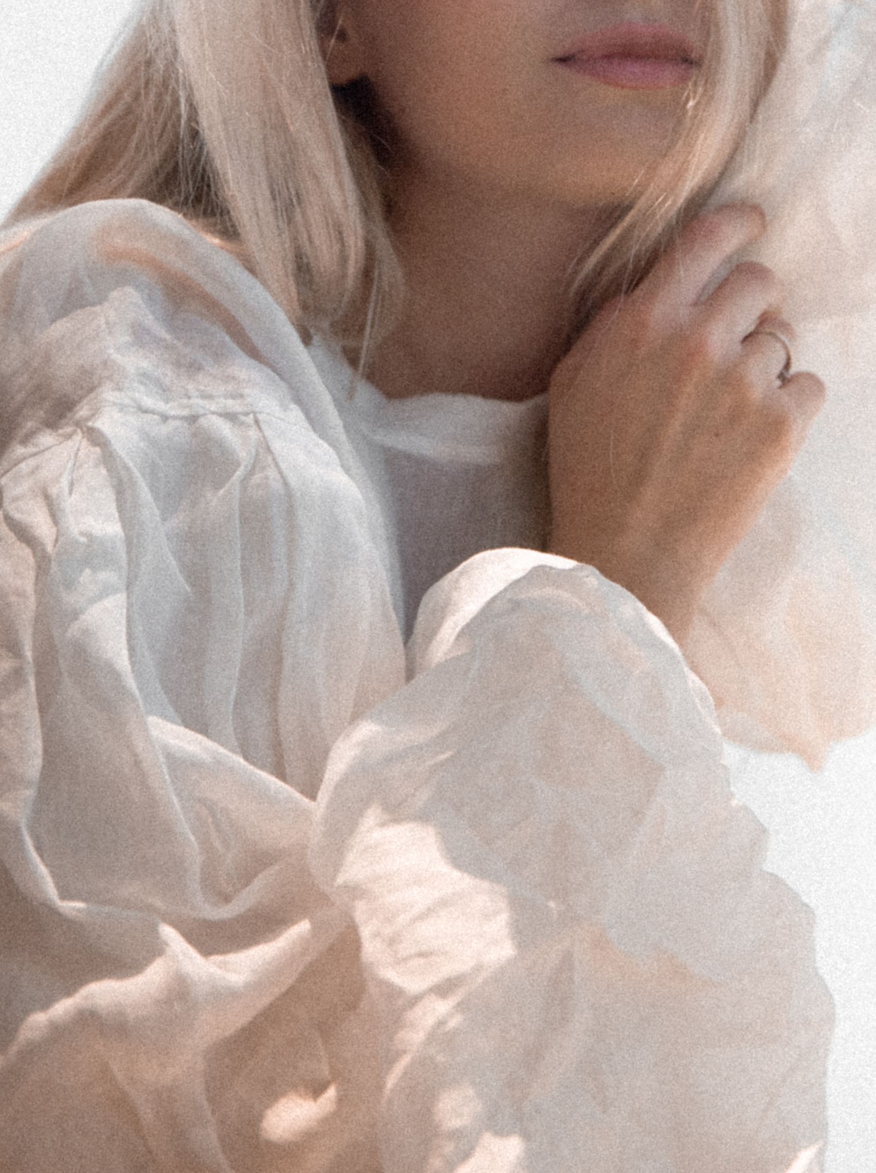 Woman in soft light and flowing fabric, symbolizing grounded presence and self-connection.